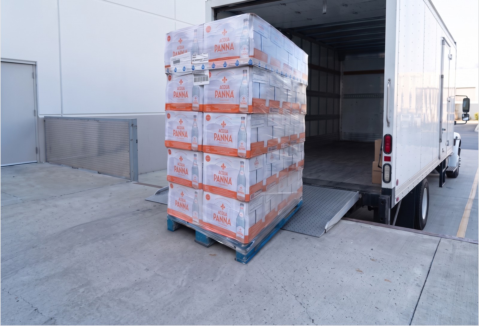 A shrink-wrapped pallet of bottled water being loaded into a freight truck